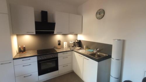 eine Küche mit Spüle und einer Uhr an der Wand in der Unterkunft Merano City Living in Meran