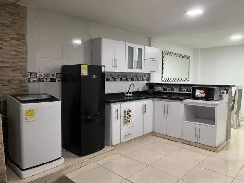 カリにあるHermosa casa en caliの白いキャビネットと黒い冷蔵庫のあるキッチン