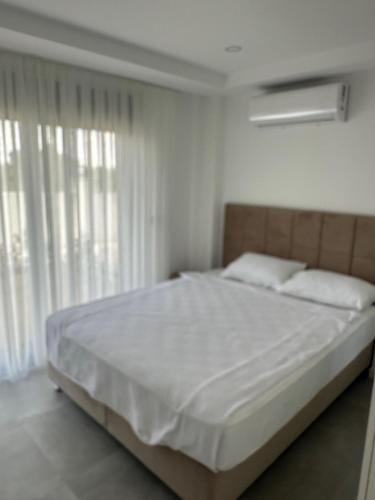 a bedroom with a large bed with white sheets and pillows at Charmante, moderne Wohnung 10 Minuten Fußweg zum Strand! in Side