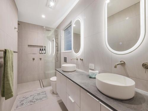 a white bathroom with two sinks and a shower at 3 Moffat Beach Holiday House in Caloundra