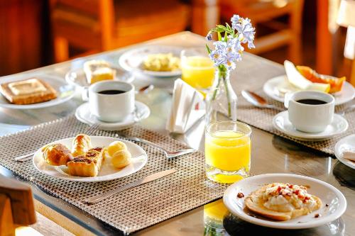 een tafel met borden ontbijtproducten en jus d'orange bij VELINN Pousada Pedras e Sonhos in Monte Verde