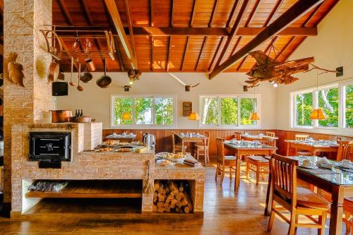 a restaurant with a fireplace and tables and chairs at VELINN Pousada Pedras e Sonhos in Monte Verde