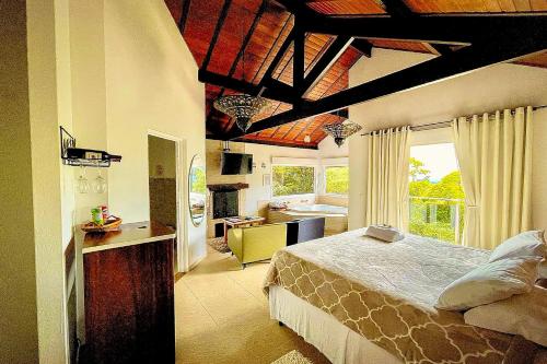 a bedroom with a large bed and a kitchen at VELINN Pousada Pedras e Sonhos in Monte Verde