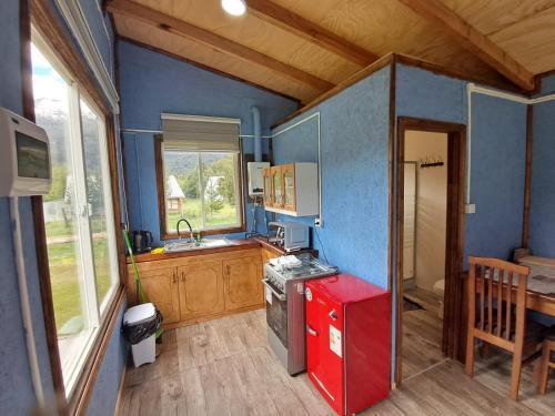 a small kitchen with blue walls and a red refrigerator at Tambera Futaleufú in Futaleufú