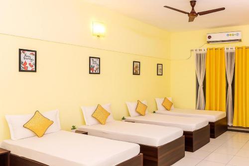 a room with three beds and a ceiling fan at Elite Stays Viman Nagar in Pune