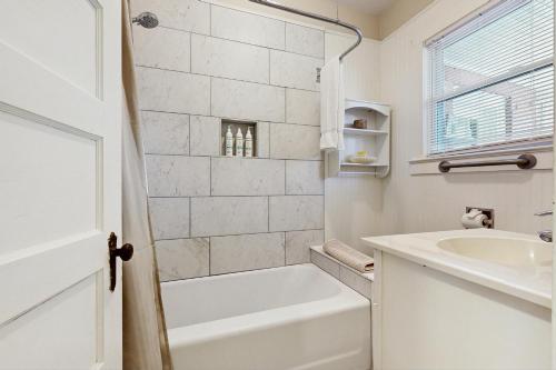 a white bathroom with a tub and a sink at Main Street Cottages in Brevard