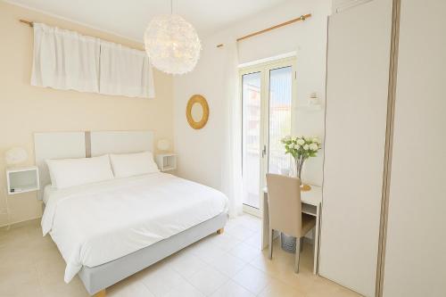 a white bedroom with a bed and a desk at Aria di sale B&B in Marina di Strongoli