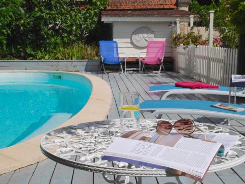 a table and chairs next to a swimming pool at L'Arbre D'Ange in Montmorillon