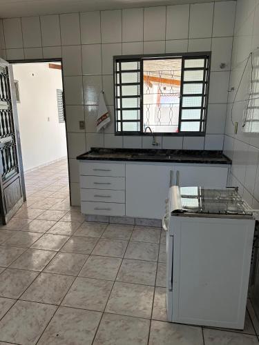 a kitchen with white appliances and a tile floor at Casa no centro in Mineiros