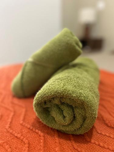a green towel sitting on top of a bed at Réveil face à la mer - Plage à 2 min - Résidence calme in Gourbeyre