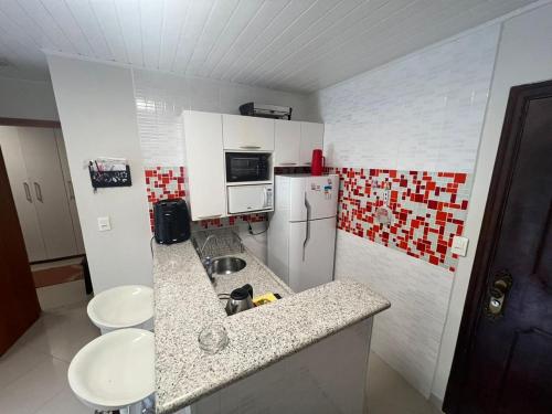 Una pequeña cocina con fregadero y refrigerador. en Cavalinho Branco 305 suíte com varanda, en Águas de Lindóia