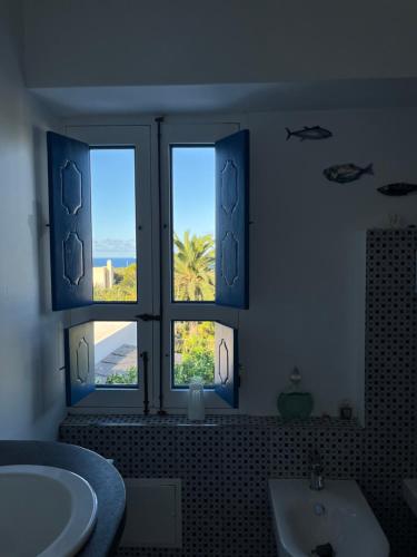 a bathroom with two windows and a tub and a sink at Casa Aimee in Stromboli