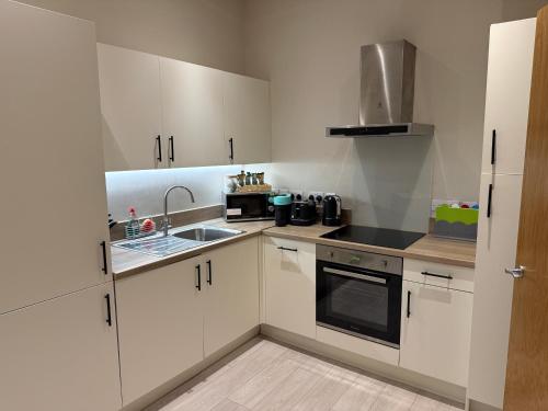 a small kitchen with white cabinets and a sink at Centenary Netho - Leeds City Centre in Central Station