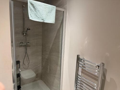 ein Bad mit einer Dusche, einem WC und einem Handtuch in der Unterkunft Centenary Netho - Leeds City Centre in Central Station