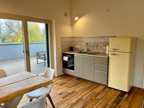 a kitchen with a refrigerator and a table with chairs at okoTime - Studio mit Dachterrasse in Birkenwerder