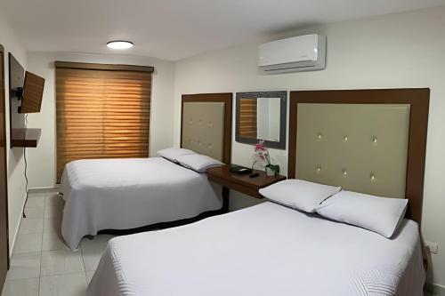 a hotel room with two beds and a table at Casa El Dorado - a 2 minutos de la Playa Miramar in Colonia Miramar