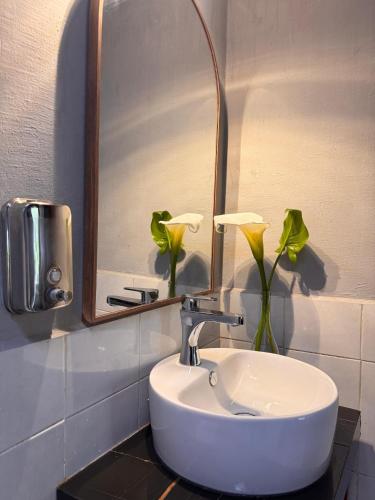 a bathroom with a sink and a mirror and flowers at cabaña de adobe las moras in San Mateo Río Hondo