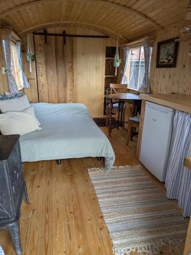 a bedroom with a bed and a table in a room at Herdershut 'Het Schoehuis', vlakbij zee in Sint Maartensbrug