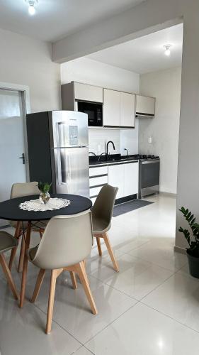 a kitchen with a table and chairs and a refrigerator at Casa moderna em Videira in Videira