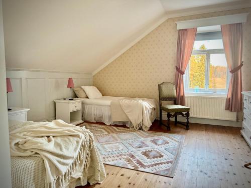 a bedroom with two beds and a chair and a window at Udden Retreat-Bed & Breakfast in Skinnskatteberg