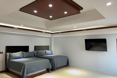 a bedroom with two beds and a flat screen tv at Loft El Tular - a 5 minutos de la Playa in Colonia Miramar