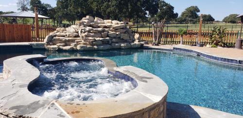 a swimming pool with a waterfall in a backyard at Private Retreat with Pond, Pool and Hot Tub in Boyd