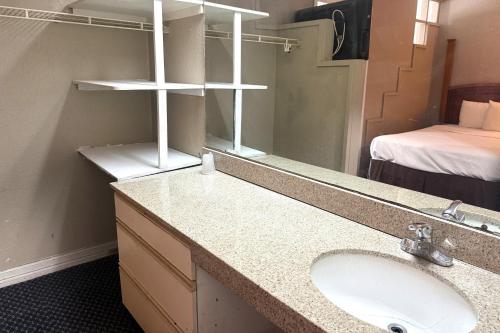 ein Badezimmer mit Waschbecken und Spiegel und einem Bett in der Unterkunft Homegate Studios & Suites San Antonio Medical Center in San Antonio