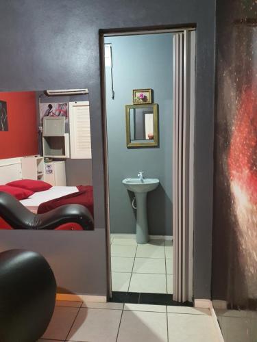 a bathroom with a mirror and a bed and a sink at Motel A 2 in Criciúma