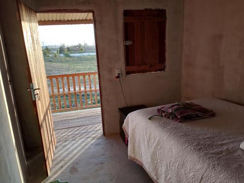 a bedroom with a bed and a door to a balcony at Pousada degamix in Barroquinha