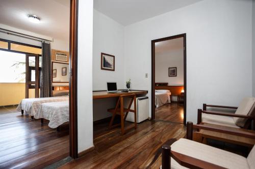 a bedroom with a bed and a desk with a mirror at Praia Sol Hotel - Leme Hotel Ltda in Serra