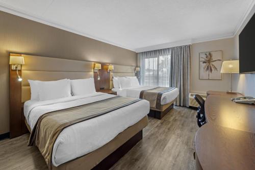 a hotel room with two beds and a desk at Best Western Hotel Universel Drummondville in Drummondville