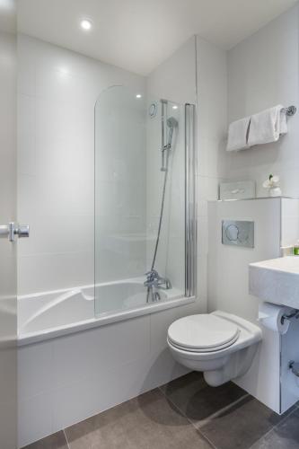 a bathroom with a shower and a toilet and a sink at Hôtel La Résidence du Berry in Versailles