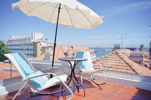 a patio with a table and chairs and an umbrella at Kasa 23 Cascais - Boutique Guest House in Cascais
