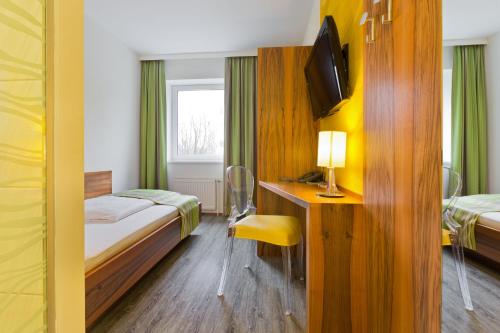 a room with two beds and a desk with a television at Motel Baden in Baden