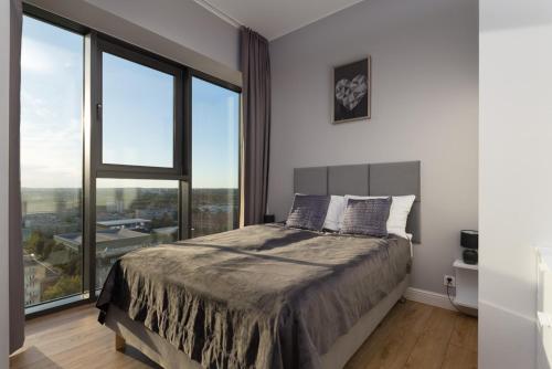 ein Schlafzimmer mit einem Bett und einem großen Fenster in der Unterkunft HANZA TOWER HIGH FLOOR Swimming Pool & Spa in Stettin