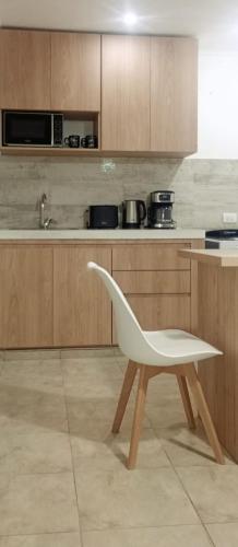 a white chair in a kitchen with wooden cabinets at Duplex Atenea in Chivilcoy