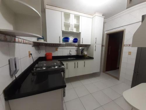 een keuken met witte kasten en een zwart aanrechtblad bij Circuito dos Trios! in Água Boa