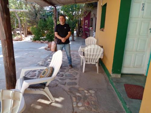 a man walking down a sidewalk with two white chairs at Hospedaje Familiar Raza Mistica in Villa Unión