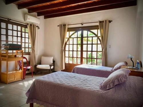 a bedroom with two beds and a chair and windows at La Casa de Don Lucho - Santa Cruz in Santa Cruz de la Sierra