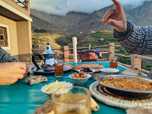 a blue table with food on it with mountains in the background at Dar Agourzi Café des Epices in Tacheddirt