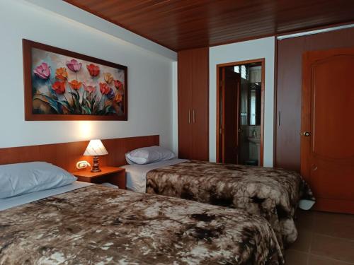 a hotel room with two beds and a painting on the wall at INTI & QUILLA Appartments in Sibundoy