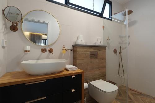 a bathroom with a sink and a toilet and a mirror at Levication Villa - Private Pool - Lakefront Migdal in Migdal