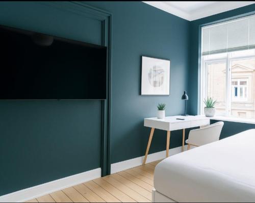 a bedroom with blue walls and a bed and a desk at Green Brook - Blue Suite in Aalborg