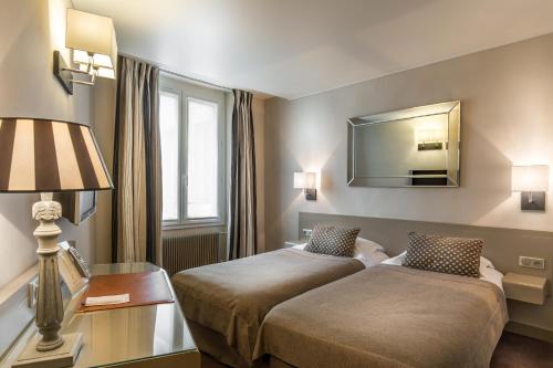 a hotel room with two beds and a mirror at Hôtel La Résidence du Berry in Versailles