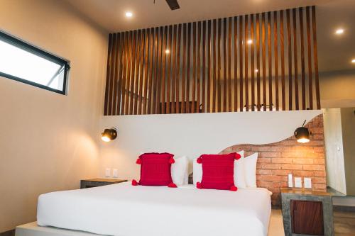 a bedroom with a white bed with two red pillows at The Garden Suite in El Rebalse