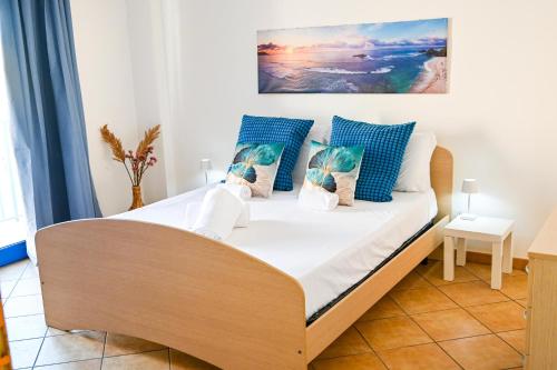 a bed with blue and white pillows in a room at Casa Azul - Social Apartment - parcheggio, clima, 200mt dal mare in Scoglitti