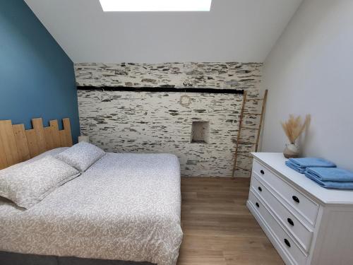 a bedroom with a white bed and a stone wall at Le Gemmois in Sainte-Gemme-sur-Loire