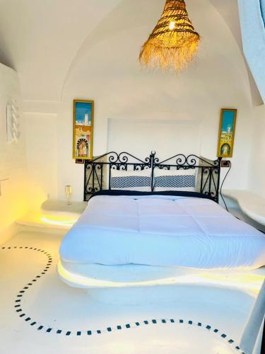 a bedroom with a large white bed with a chandelier at Casa Dea - bungalow Mykonos in Hammamet Sud