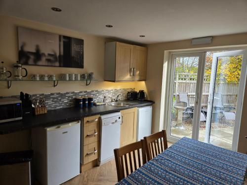 a kitchen with white appliances and a table with a blue table at Farthing Cottage in Norwich