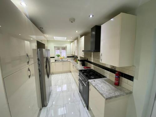 a white kitchen with a stove and a refrigerator at Tooting Stays in London